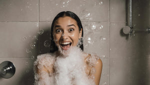 surprised happy woman in the shower covered with bubbles