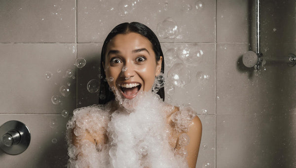 surprised happy woman in the shower covered with bubbles
