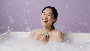 happy laughing woman in the bath holding a soap