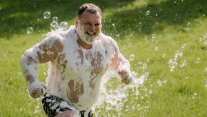 happy soapy man running through grassy field