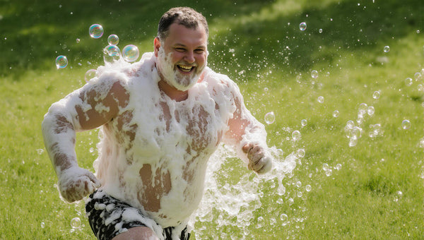 happy soapy man running through grassy field